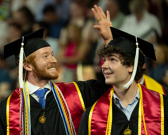 Two students in graduation regalia at 2024 Undergraduate Commencement